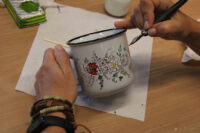 Kubek porcelanowy - wypełnienie stalówką wzoru kwiatowego w kolorze czerwonym.