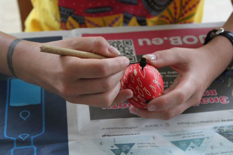 Pisanie kiską wzoru zoomorficznego na jajku zabarwionym w kolorze czerwonym