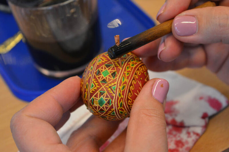 Pisanie kiską wzoru geometrycznego na jajku zabarwionym w kolorze brązowym