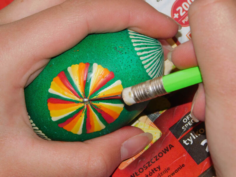 Pisanie szpilką wzoru geometrycznego na jajku zabarwionym w kolorze zielonym