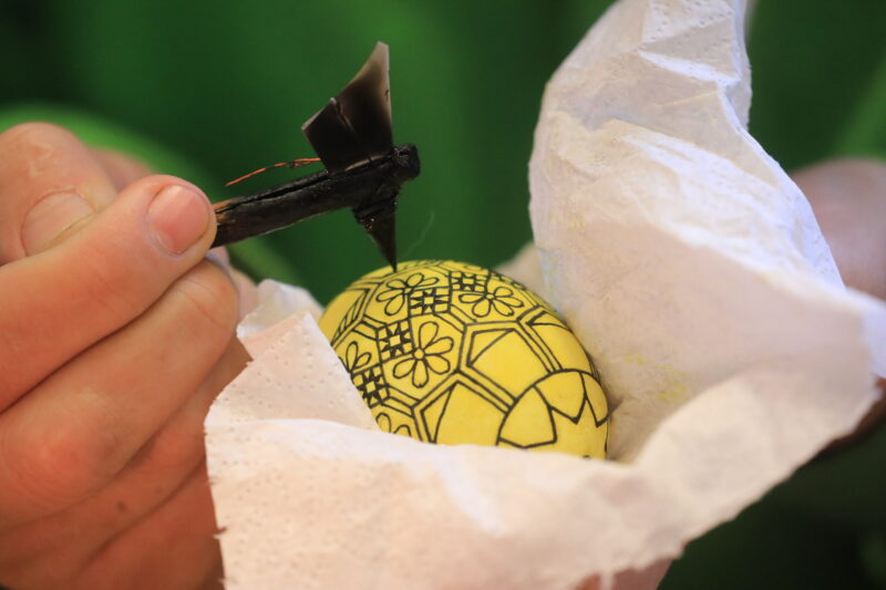 Pisanie woskiem patyczkiem z metalowym pisakiem po powierzchni jajka.